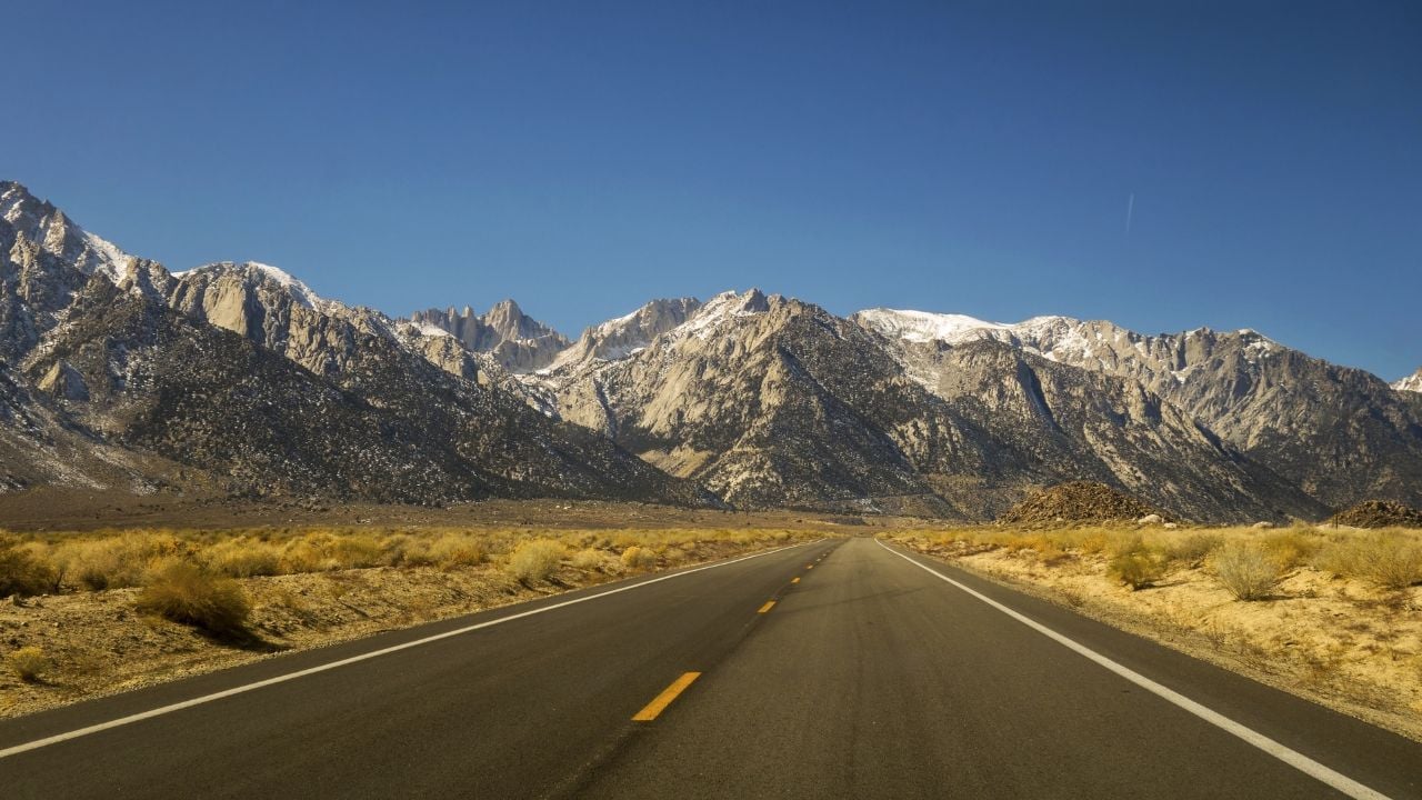 Driving Iconic California State Highway 395 in Owens Valley on Eastern Flanks of Sierra Nevada Mountains with Distant Mount Whitney on Horizon