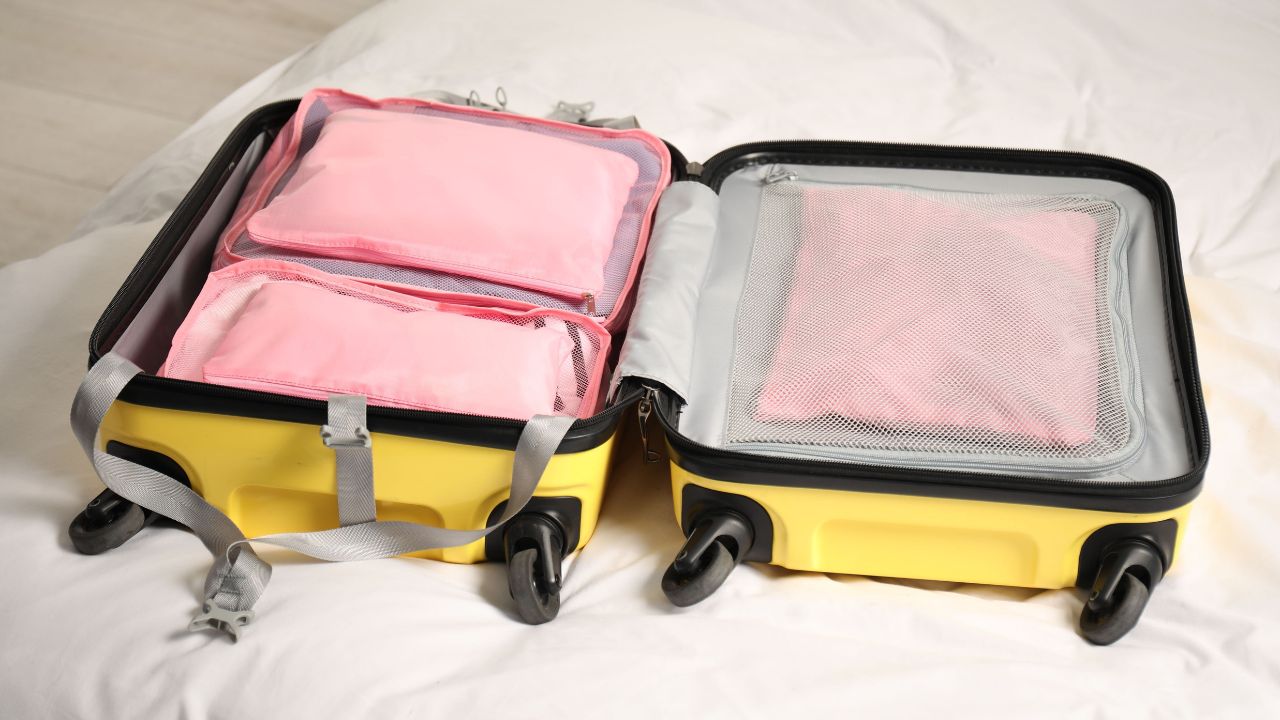 Open suitcase with packing cubes on bed indoors