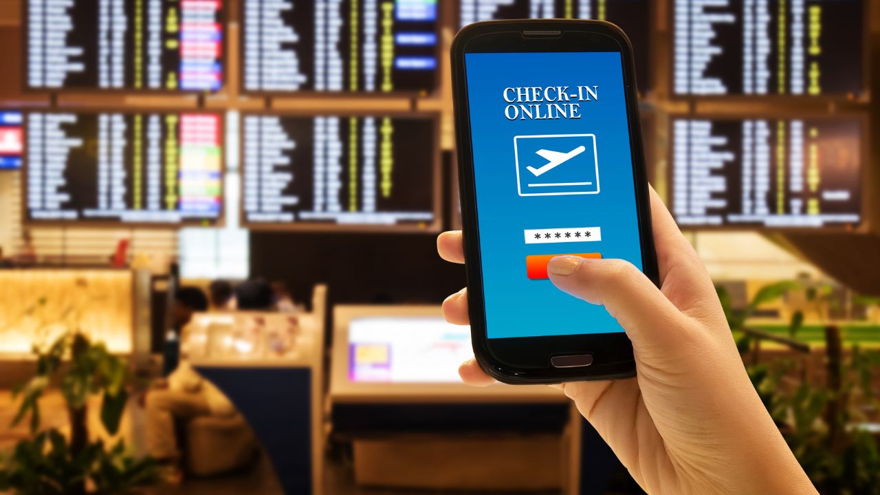 Traveler smartphone app concept. Close up of woman hand in international airport use mobile phone for check in online with flight information board background, checking her flight. Anonymous face