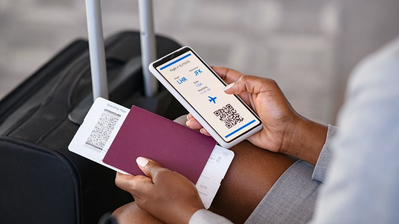Close up hand of black businesswoman checking flight eticket on phone while holding passport and boarding pass. African american woman hand checking online travel plane ticket on mobile phone.