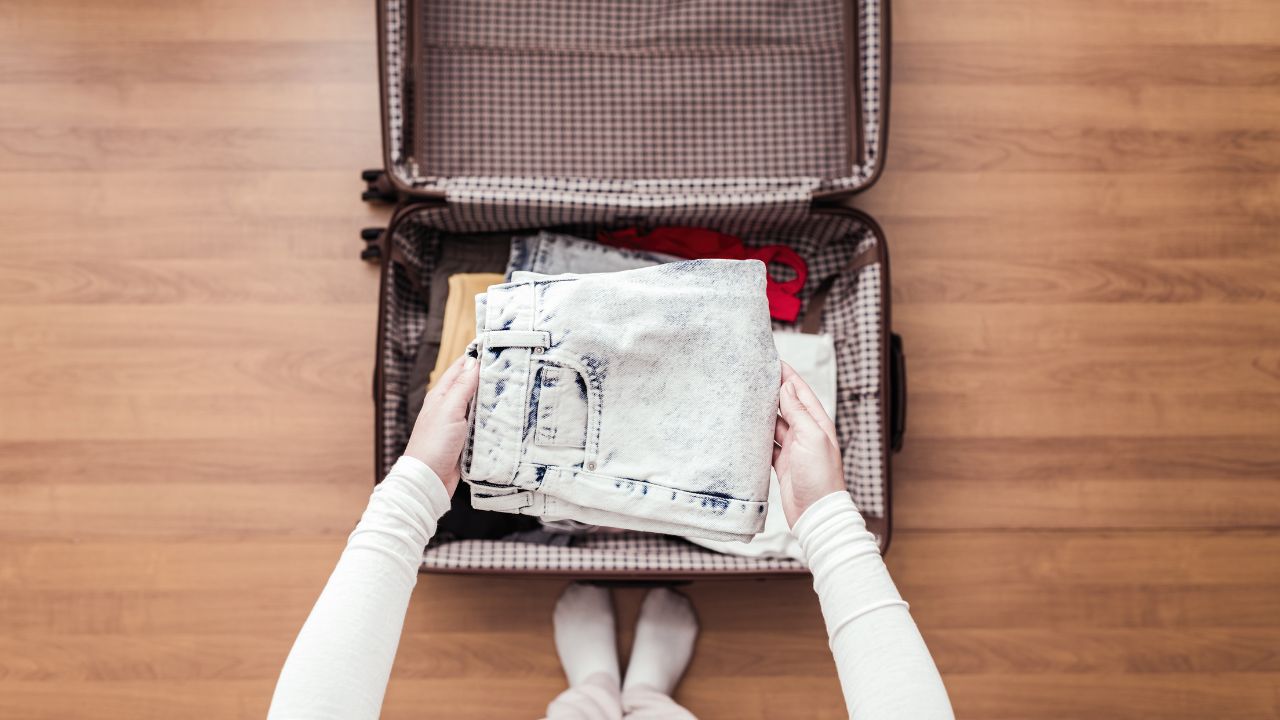 Top view of woman hands packing a luggage for a new journey.