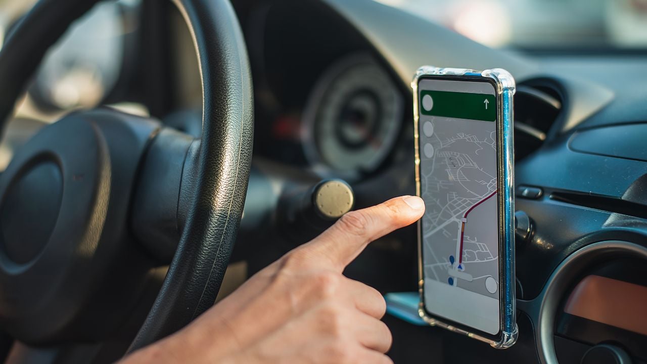 Man driving while using the mapping app on his smartphone to find his location. using a phone as a navigation device in a car