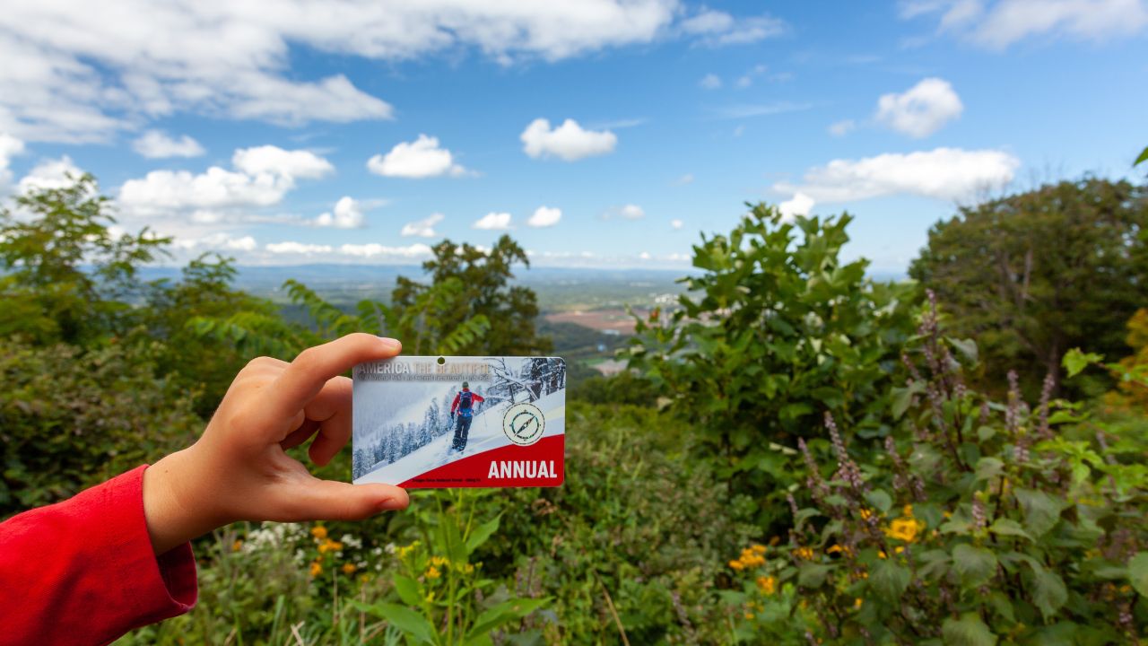 Shenandoah Valley, VA, USA 09/27/2020: A Girl is holding an 'America the beautiful' annual pass card against vista of Shenandoah. It grants unlimited entry to all federal national parks in the USA.