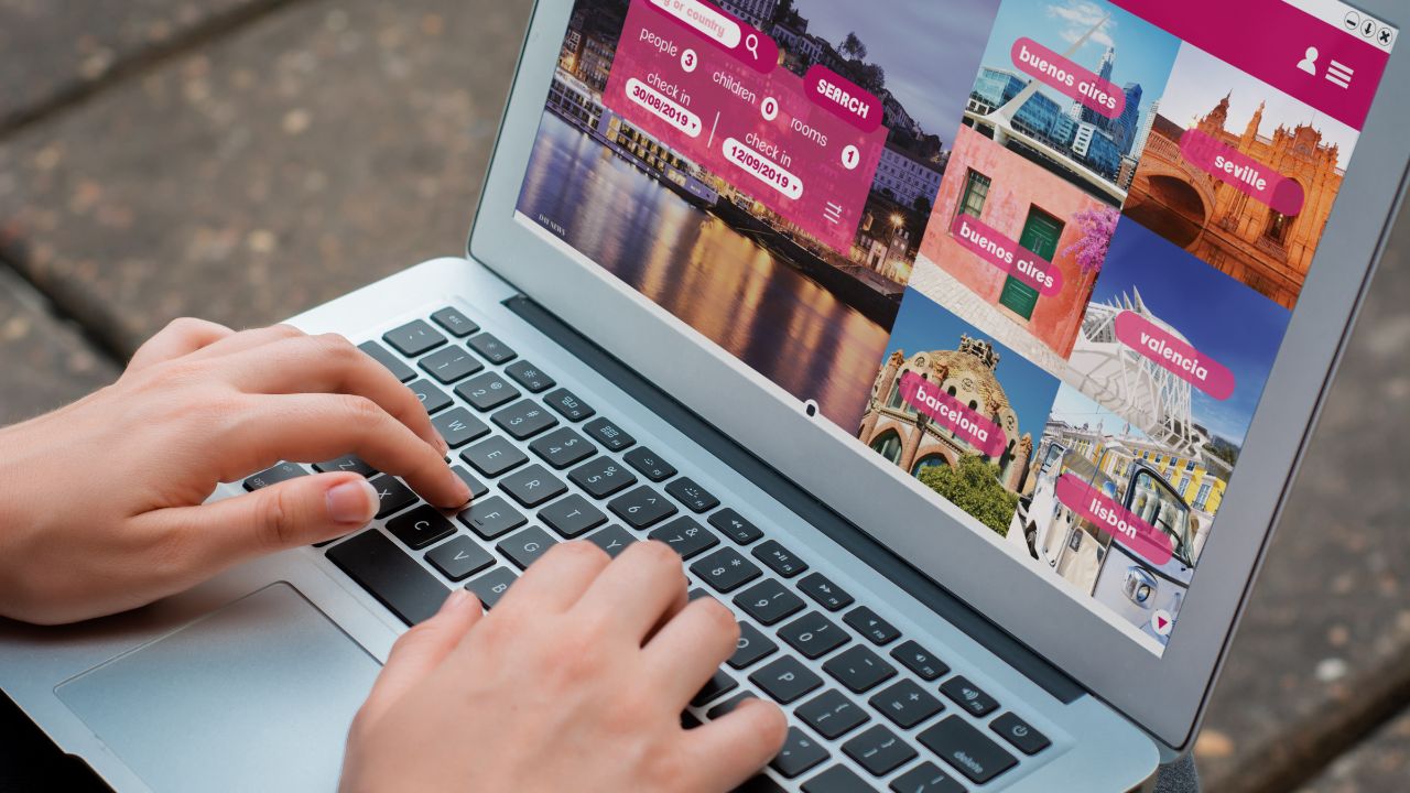 Close up view of woman with laptop booking a hotel on website. Travel concept. All screen graphics are made up by us