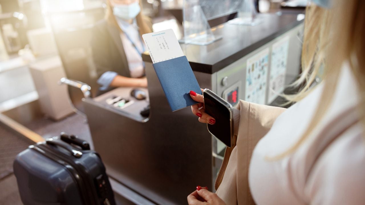 Woman holding passport and tickets near reception desk