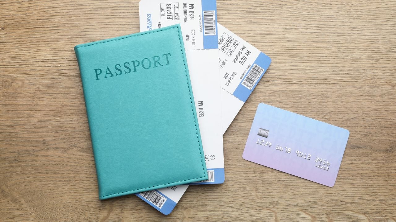 Travel agency. Flight tickets, passport and credit card on wooden table, flat lay