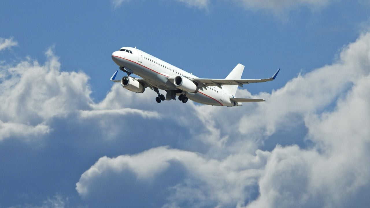 Zoom photo of passenger airplane taking off reaching altitude above clouds in deep blue sky