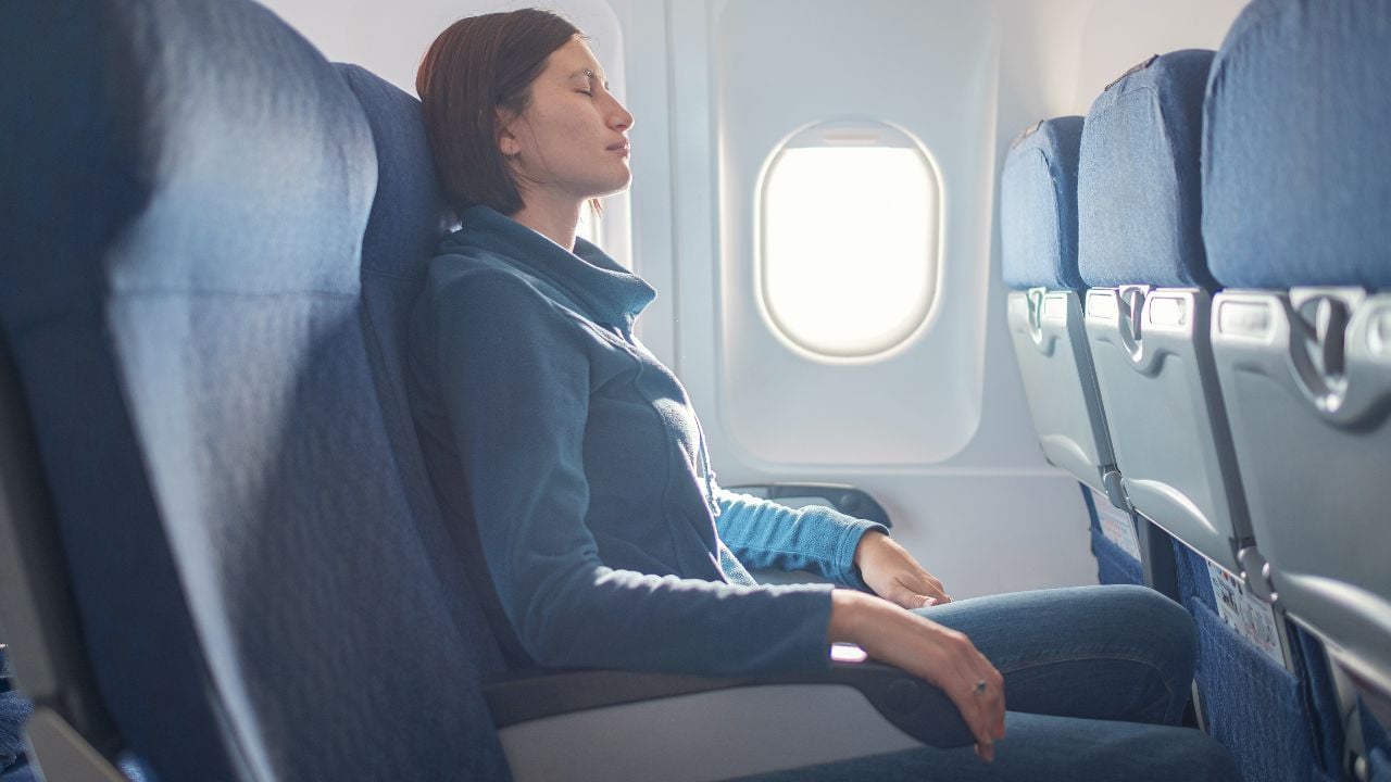 Fear of flying woman in plane sick with stress headache and motion sickness or airsickness. travel with airplane with aerophobia is afraid to fly, sitting on seat of plane.