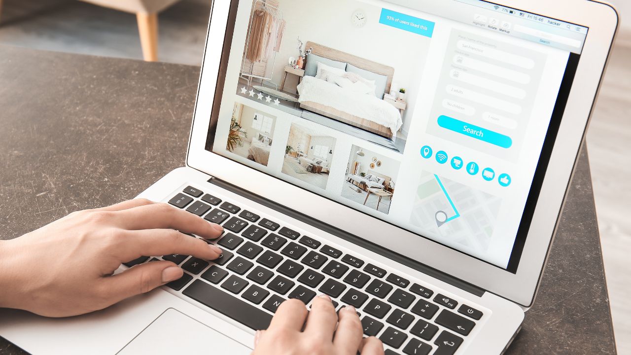 Woman with laptop booking room in hotel online at home