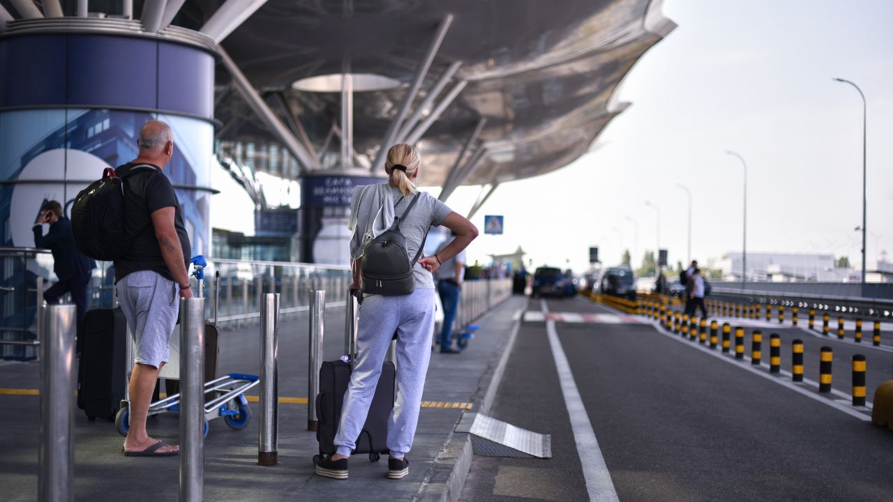 couple travelers with luggage waiting taxi in airport