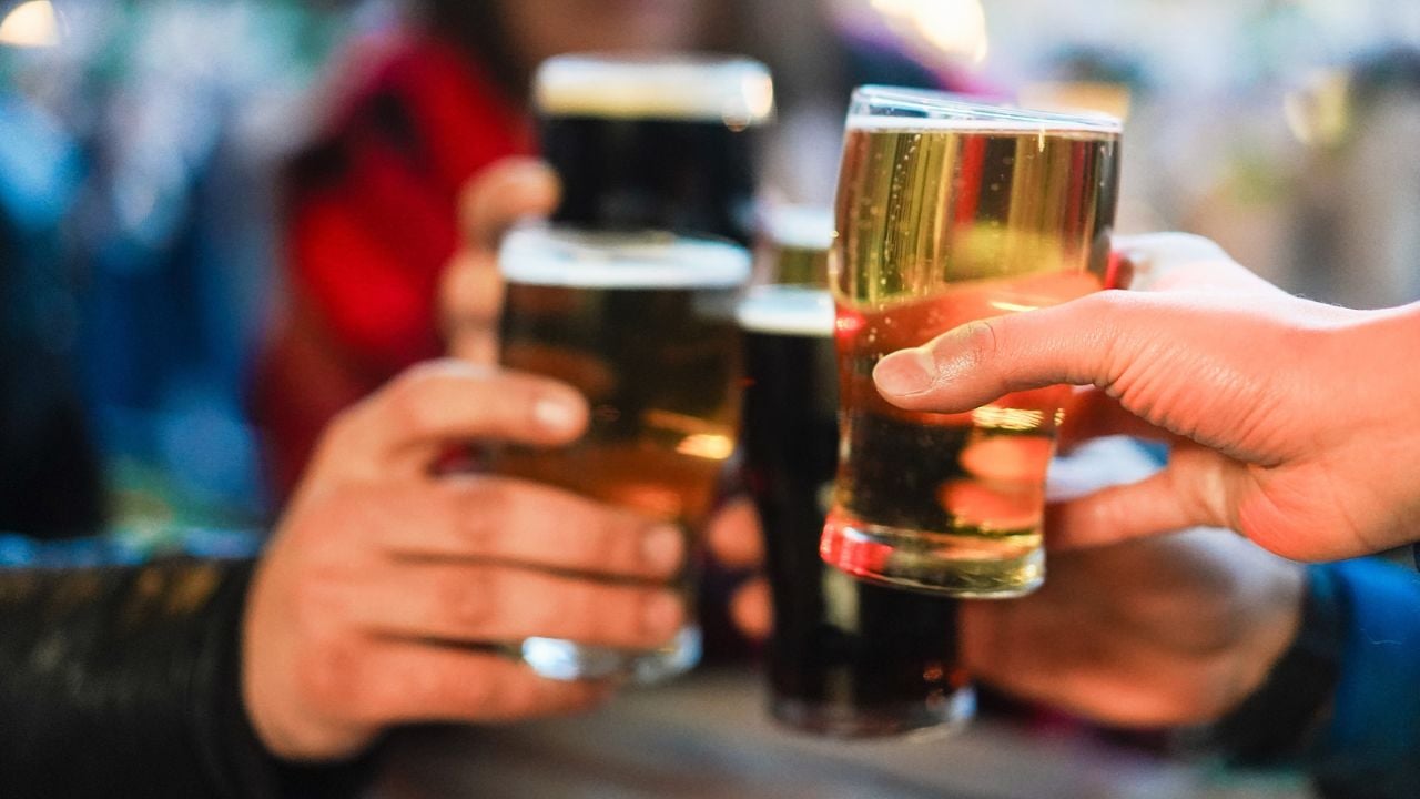 Young group of people having fun cheering with beer outdoor at pub restaurant - Winter lifestyle and party concept - Soft focus on right hand