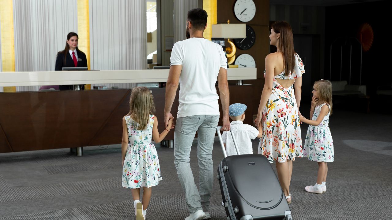 Family of five enters to the hotel lobby to check in at the reception for vacation.