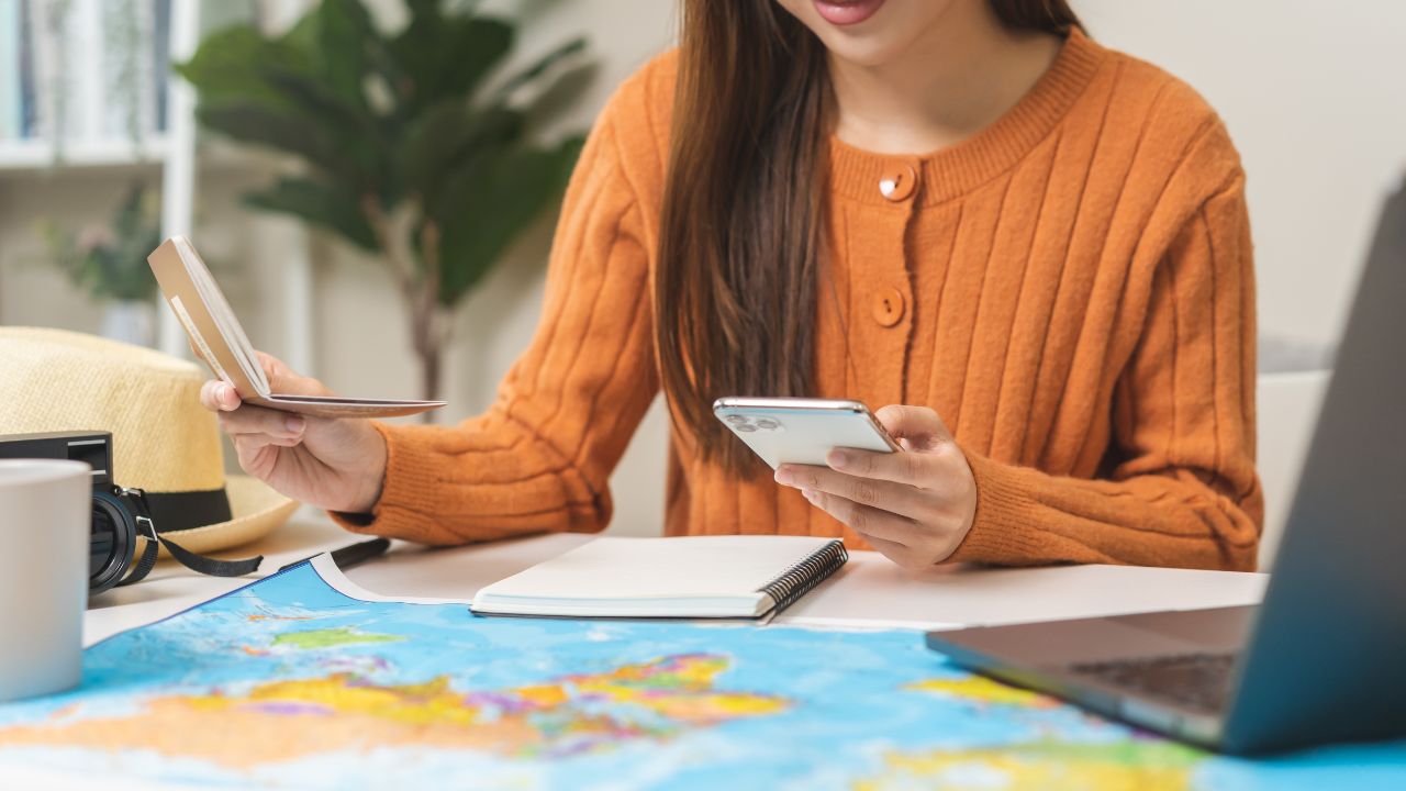Travel planning, vacation, holiday trip, asian young tourist woman, girl hand using mobile phone, cellphone book flight ticket or check in online with passport, preparation for journey voyage trip.