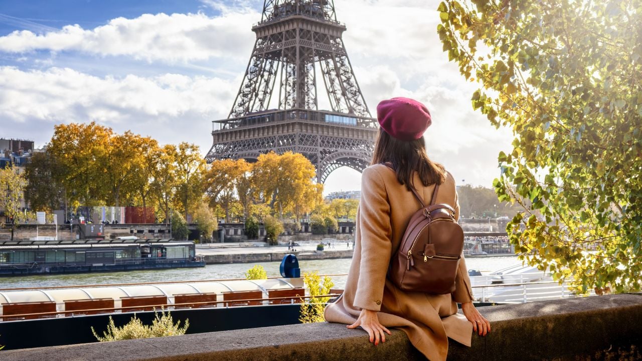 Tourist sitting by the Seine with a view of the Eiffel Tower in Paris