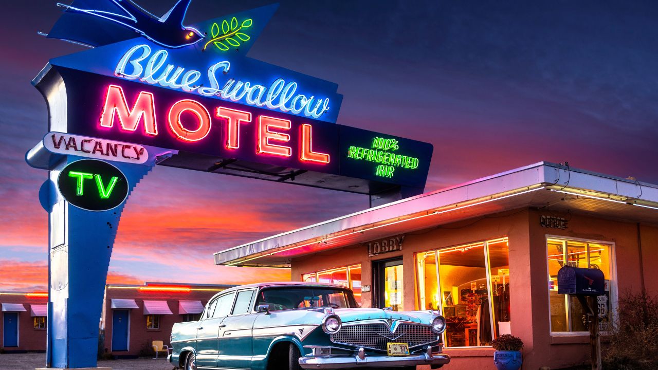 Tucumcari, NM - USA - March 16 2022: Historic Blue Swallow Motel on Route 66 with Neon and Classic Car at Sunset.