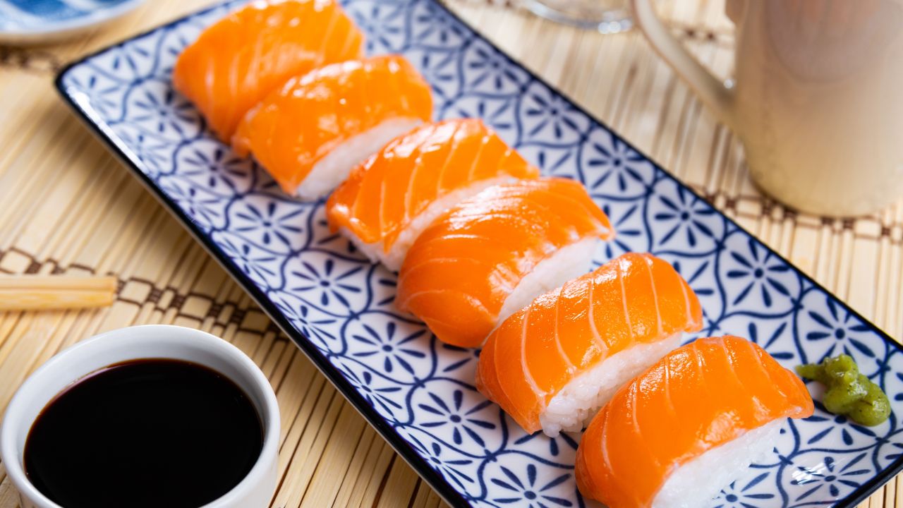 Salmon Sushi on white plate with soy souse on Makisu table. Japanese seafood.