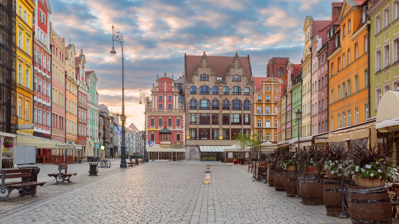 Morning view of colorful buildings on Rynek Square in Wroclaw, Poland, with street lamps and a partly cloudy sky