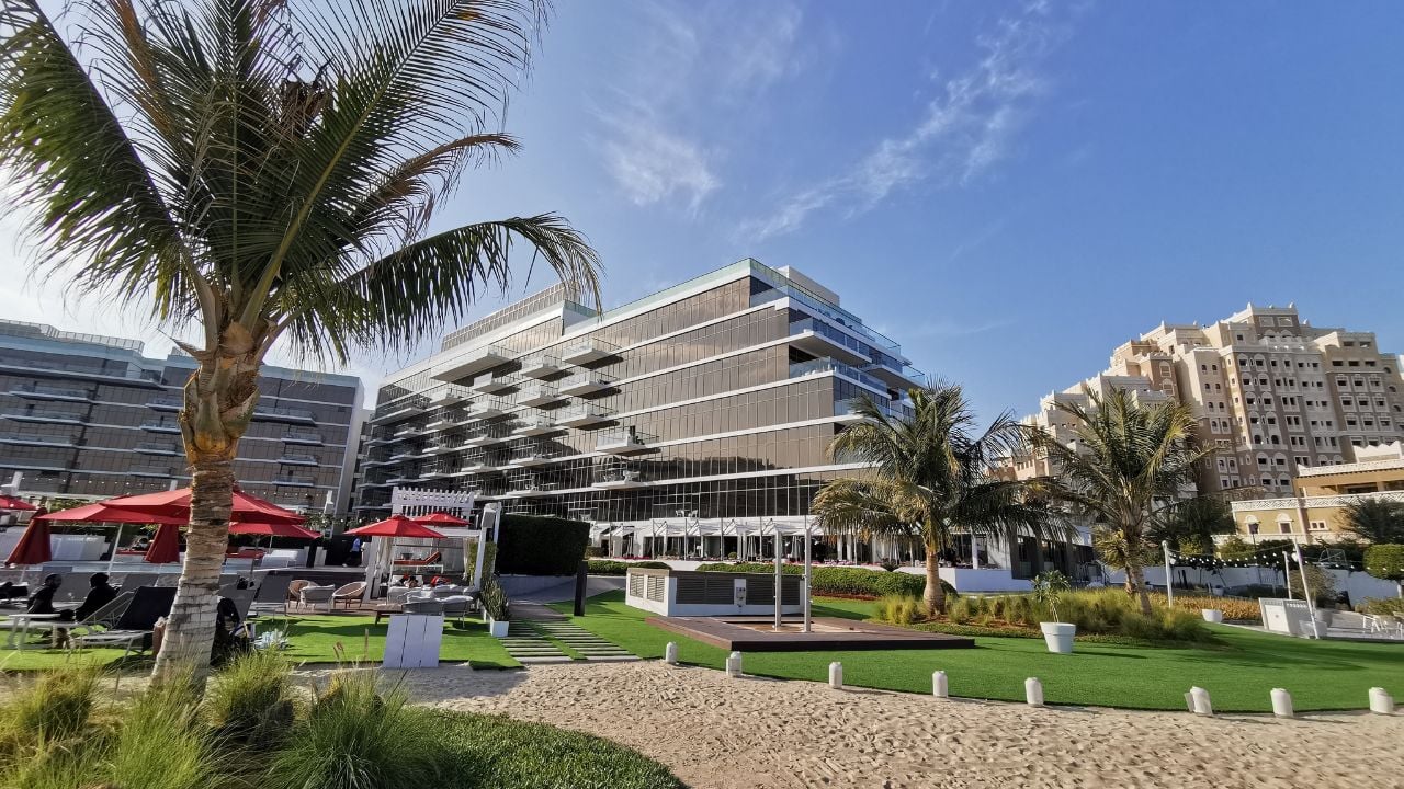 Dubai, UAE - 14 of January, 2024. Coconut tree at the beach and hotel building of Th8 Palm Beach Resort, Vignette collection