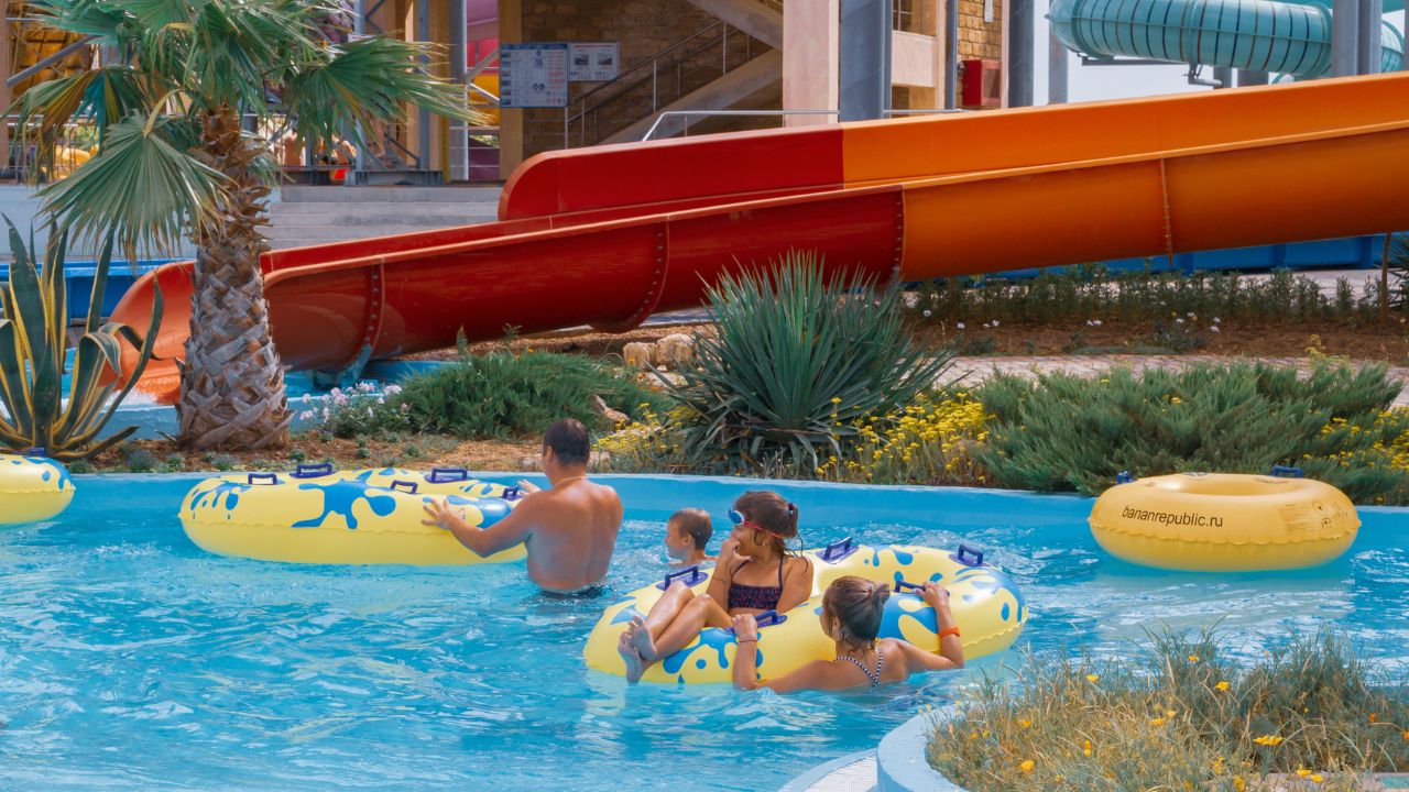Families relax and float along a lazy river at a family-friendly waterpark on a summer day
