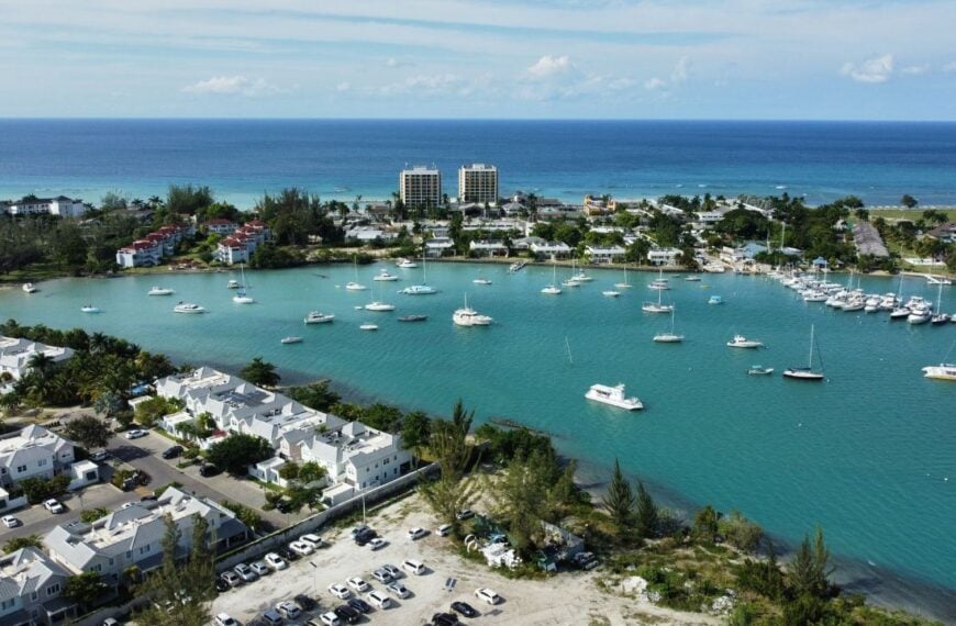 An aerial of hotels on a beach covered with greenery against a turquoise sea in Montego Bay, Jamaica