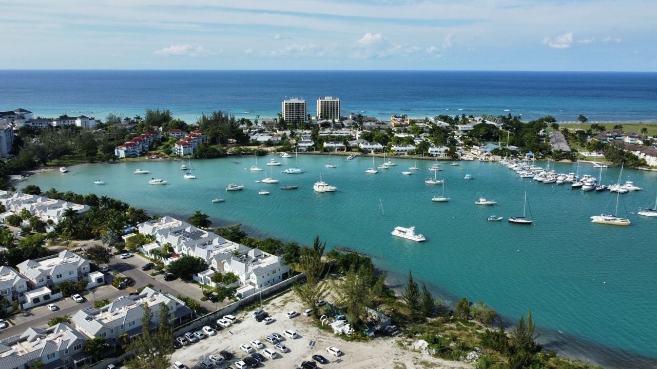 An aerial of hotels on a beach covered with greenery against a turquoise sea in Montego Bay, Jamaica