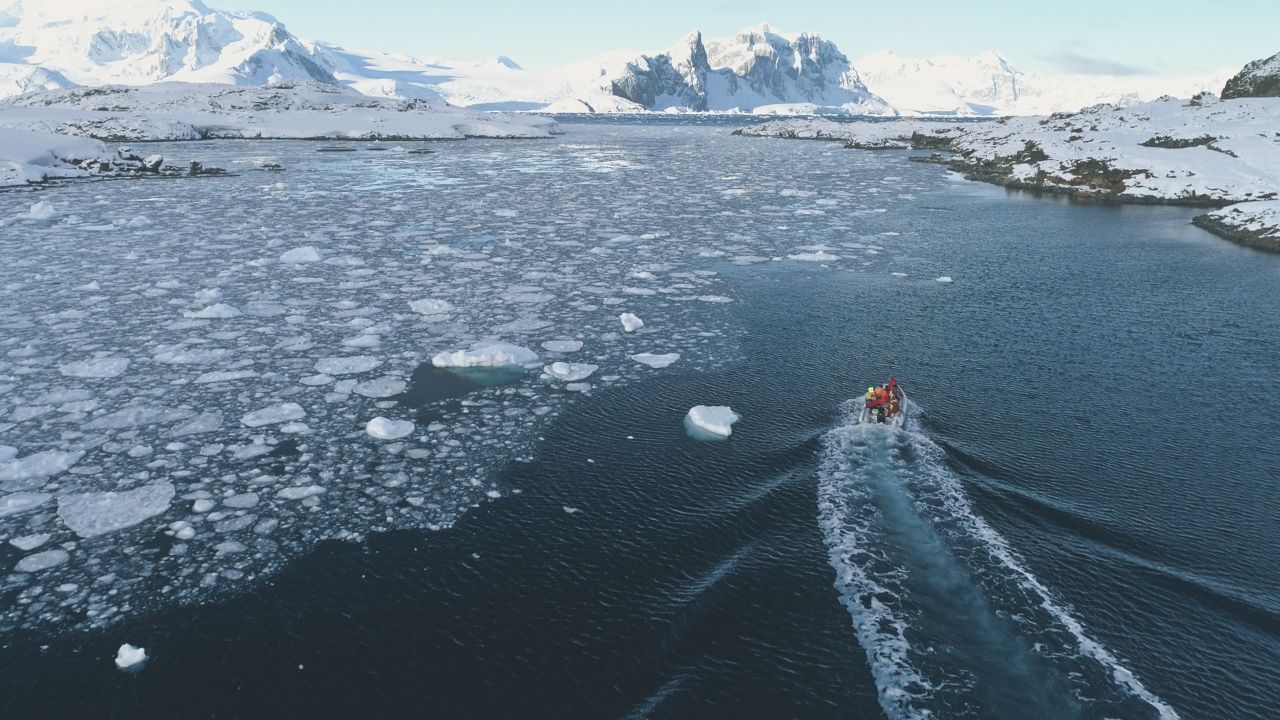 Zodiac Boat in Antarctica Ocean Aerial. Drone Flight Overview of South Pole Antarctic Glacier. Rubber Boat Float in Frozen Winter Water Landscape Among Ice Shore.