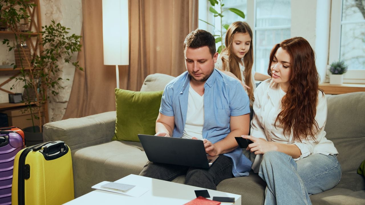 Family planning a trip at home with suitcases and a laptop