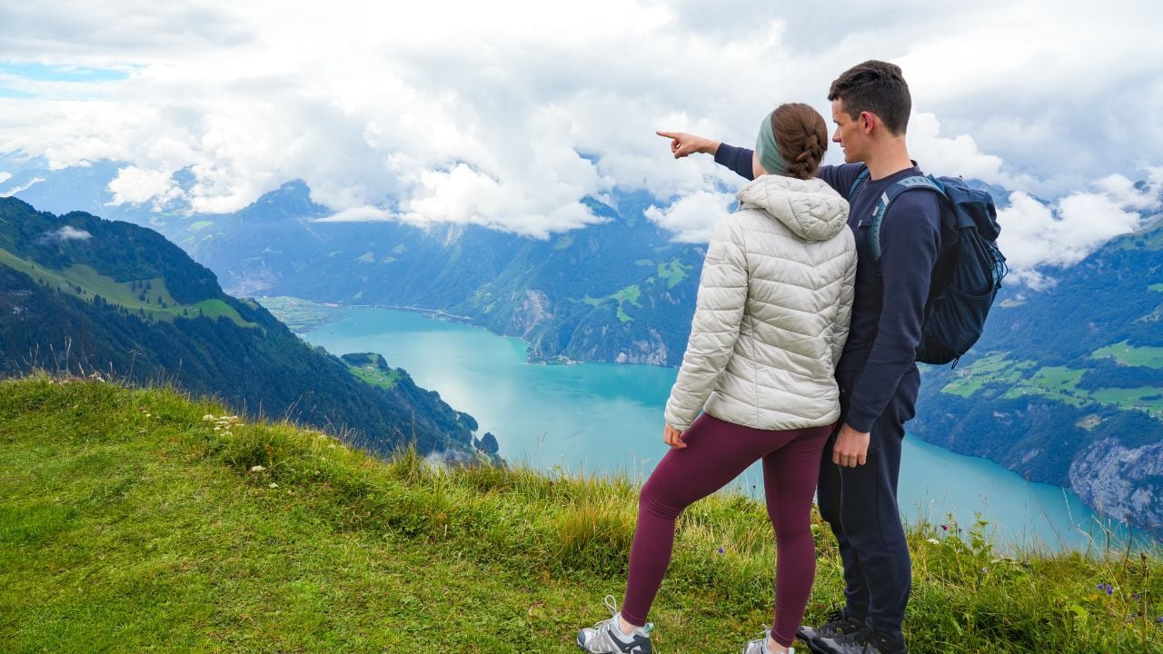 Couple standing on a hilltop in the Swiss Alps overlooking a mountain lake