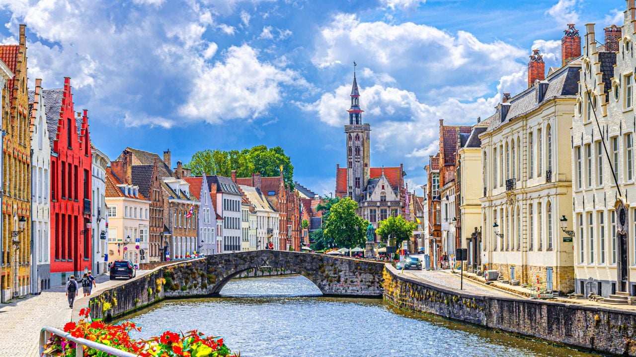 Bruges cityscape with the Spiegelrei canal, Poortersloge tower, King’s Bridge, and medieval buildings in Belgium