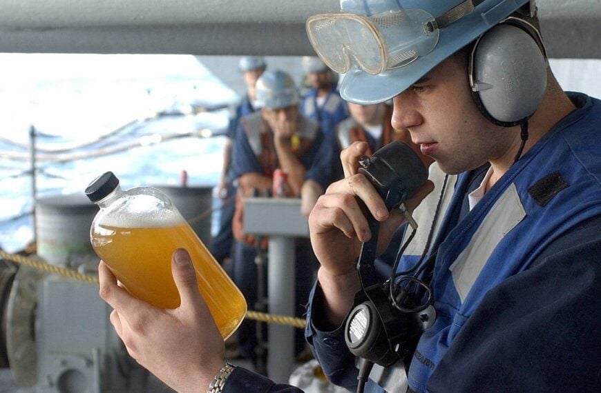 Machinist’s Mate Fireman Michael Barton from Ashdown, Ark., examines a sample of Diesel Fuel Marine (DFM) and reports his findings to the carrier’s Oil Lab during a replenishment at sea (RAS) evolution.