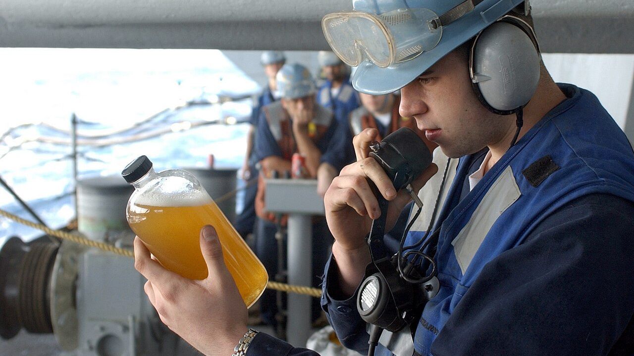 Machinist’s Mate Fireman Michael Barton from Ashdown, Ark., examines a sample of Diesel Fuel Marine (DFM) and reports his findings to the carrier’s Oil Lab during a replenishment at sea (RAS) evolution.