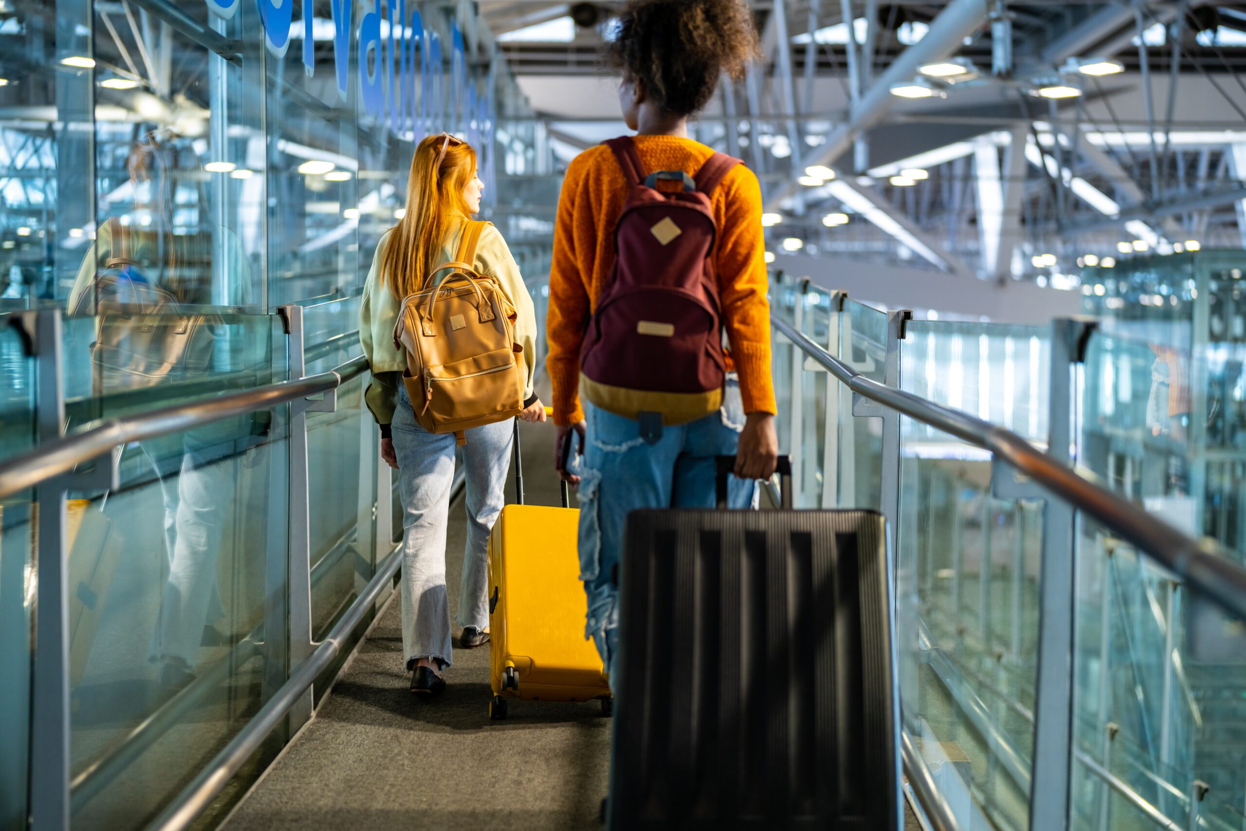 woman friends holding passport and luggage walking together to airline check in counter in airport terminal. Attractive girl enjoy and fun travel on holiday vacation with airplane transportation