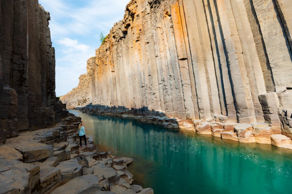 A hiker admires the beauty of Studlagil Canyon.