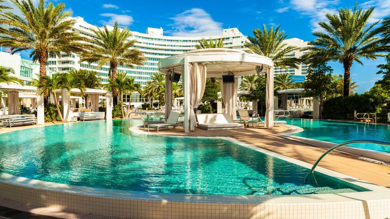 A large resort pool lined with palm trees and private cabanas offers a calm, upscale setting designed for relaxation, wellness, and all-day lounging by the water.