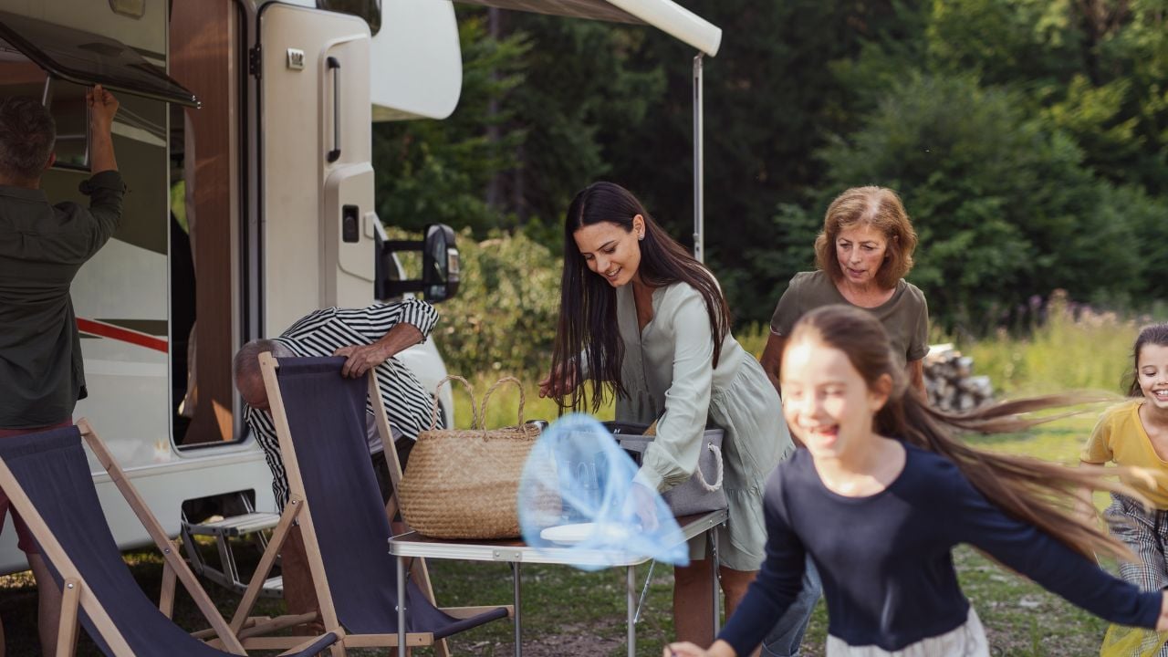 Multi-generation family unpacking and talking by car, caravan holiday trip.