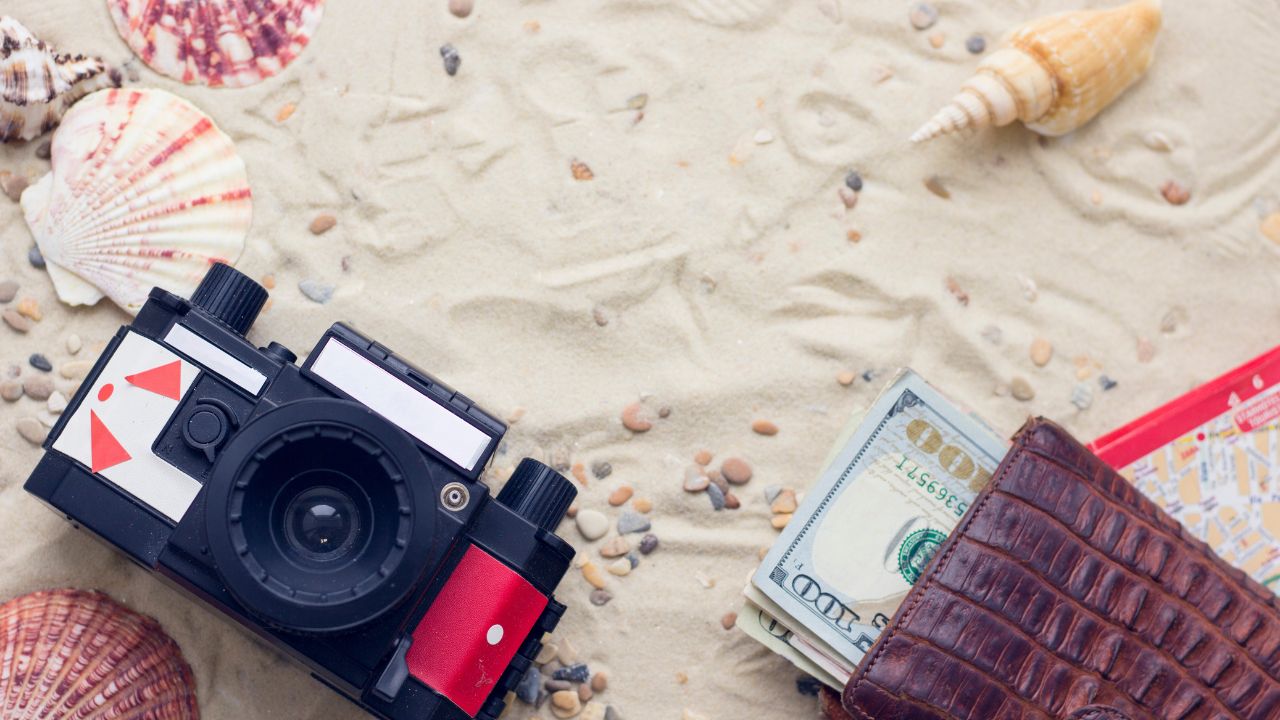 Vintage roll-film camera and travel accessories on sand