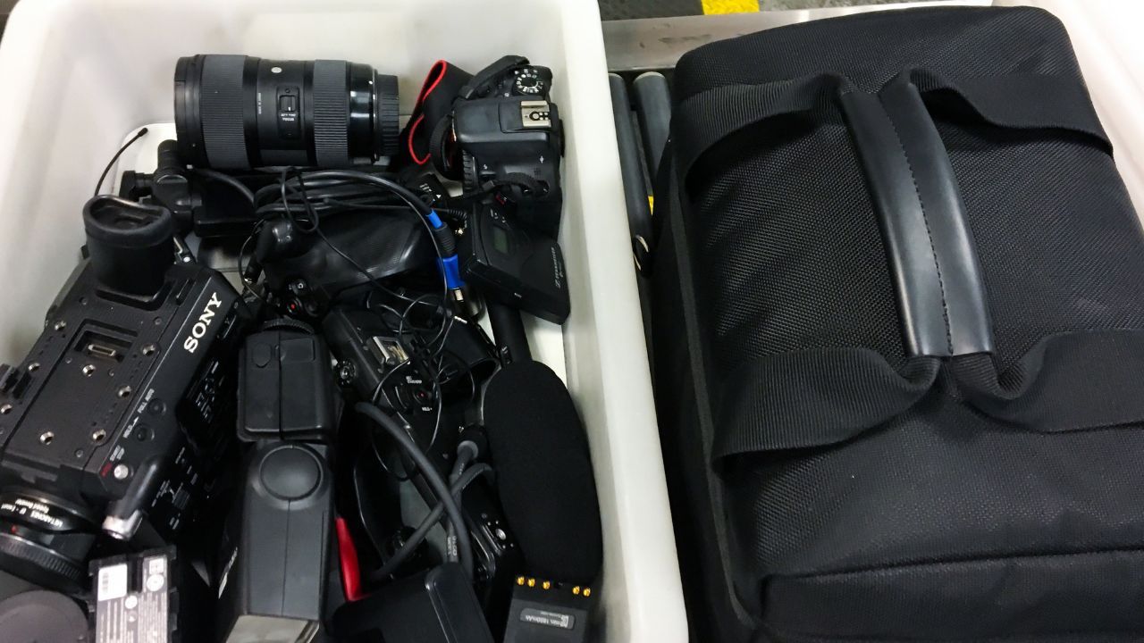 Camera bag and gear at an airport security conveyor belt