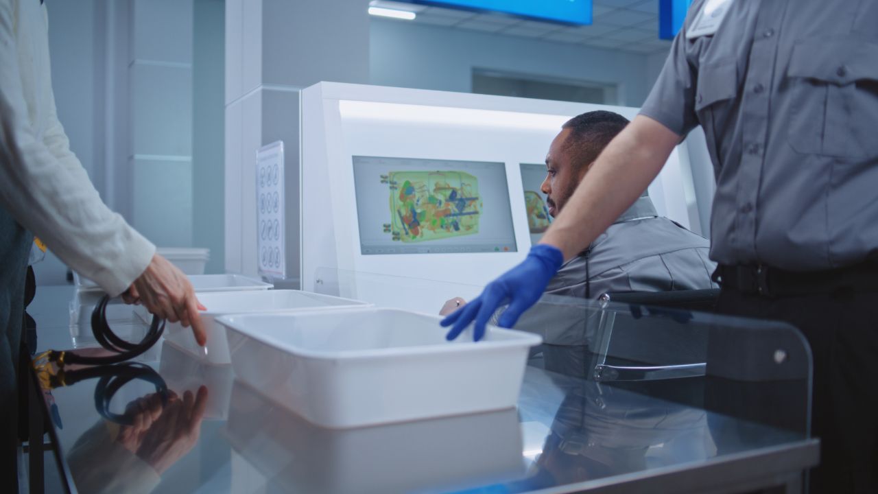 Passengers placing personal belongings in trays at airport security