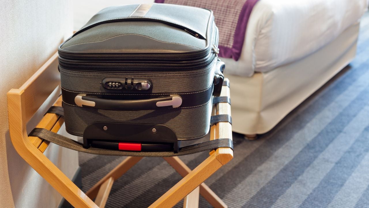 Hotel room with a suitcase on the luggage place and the bed