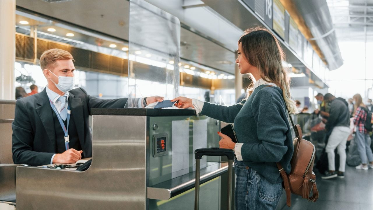 Standing by the table with employee. Young female tourist is in the airport at daytime.