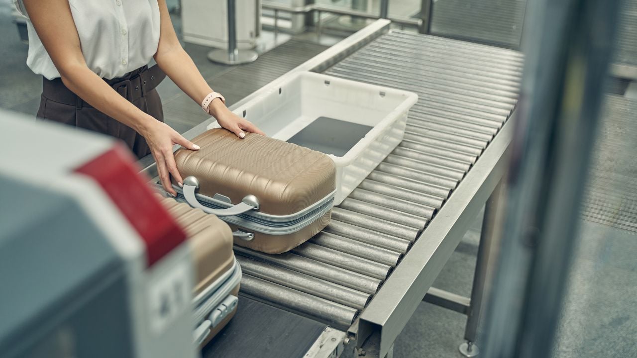 Competent traveler putting her suitcases on the tape for doing X-ray checkup before flight
