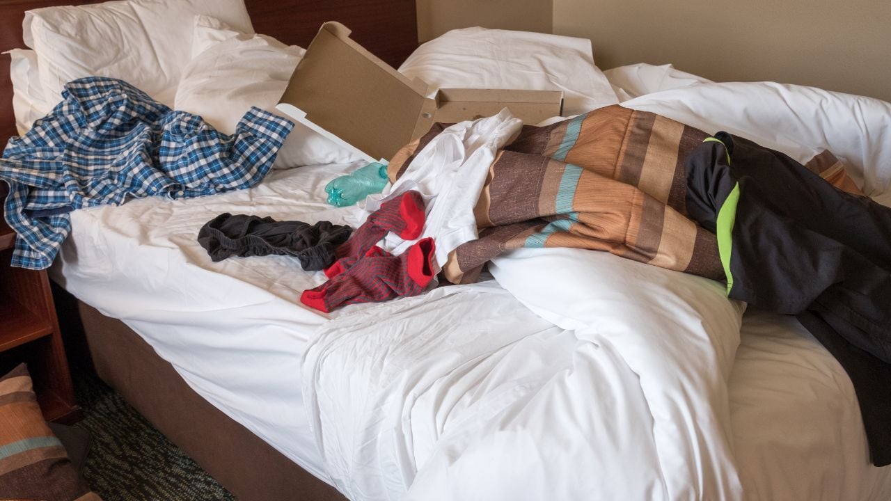 messy hotel room bed after a night of partying