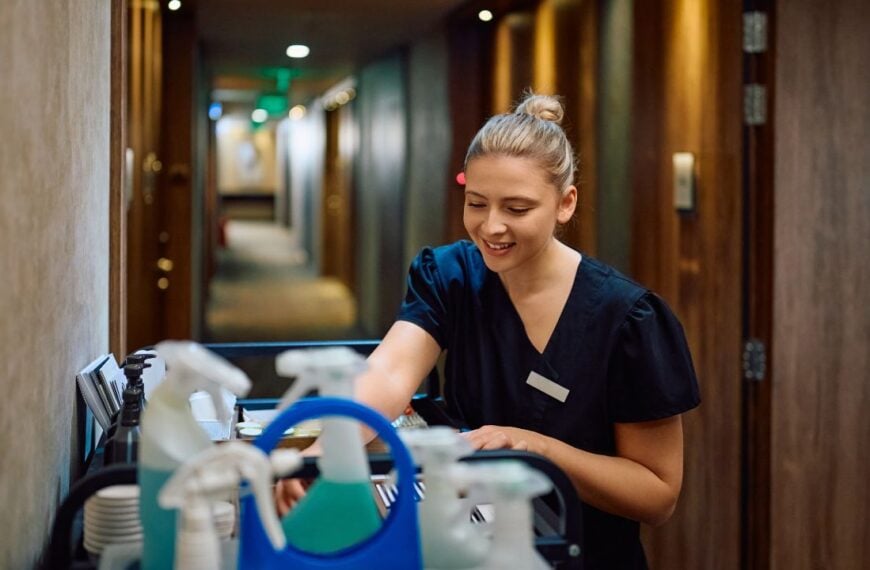 Happy maid cleaning guest rooms while working in a hotel. Copy space.