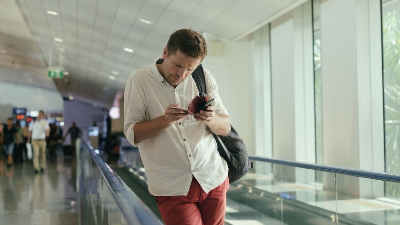 A traveler checks their phone for a boarding pass at the last minute, a common delay that can slow down the boarding process at the gate