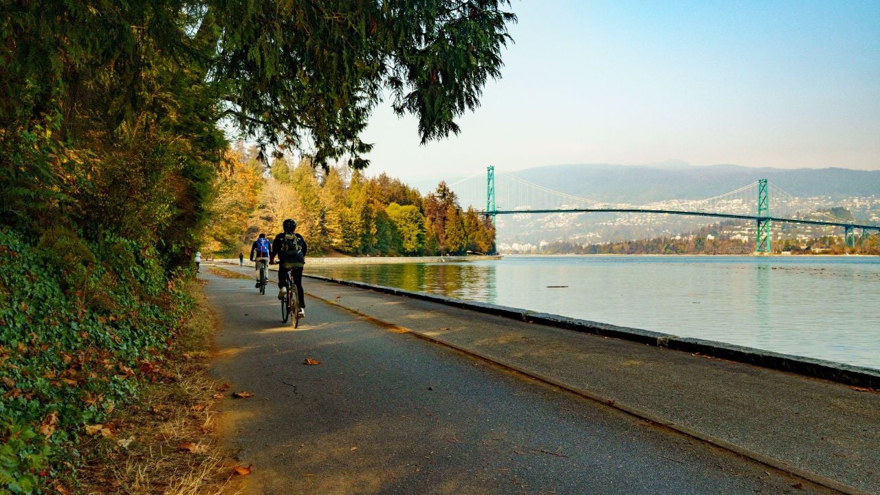 A beautiful shot of fall in Stanley Park with people walking along the water in Vancouver, Canada