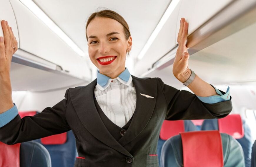 Cheerful woman flight attendant standing in aircraft passenger salon