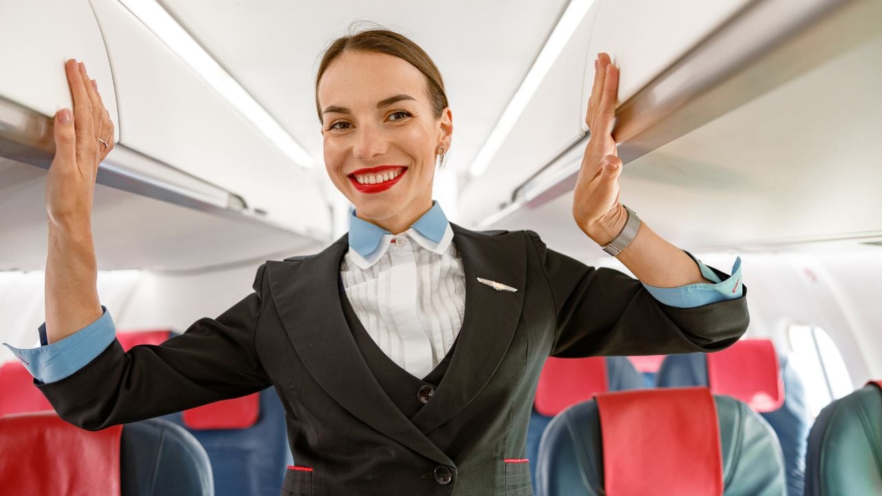 Cheerful woman flight attendant standing in aircraft passenger salon