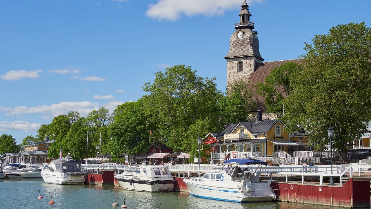 Finland, Naantali - June 9, 2023. Embankment in the old center of the Finnish town of Naantali in Europe: Lutheran church, old wooden houses, yachts.