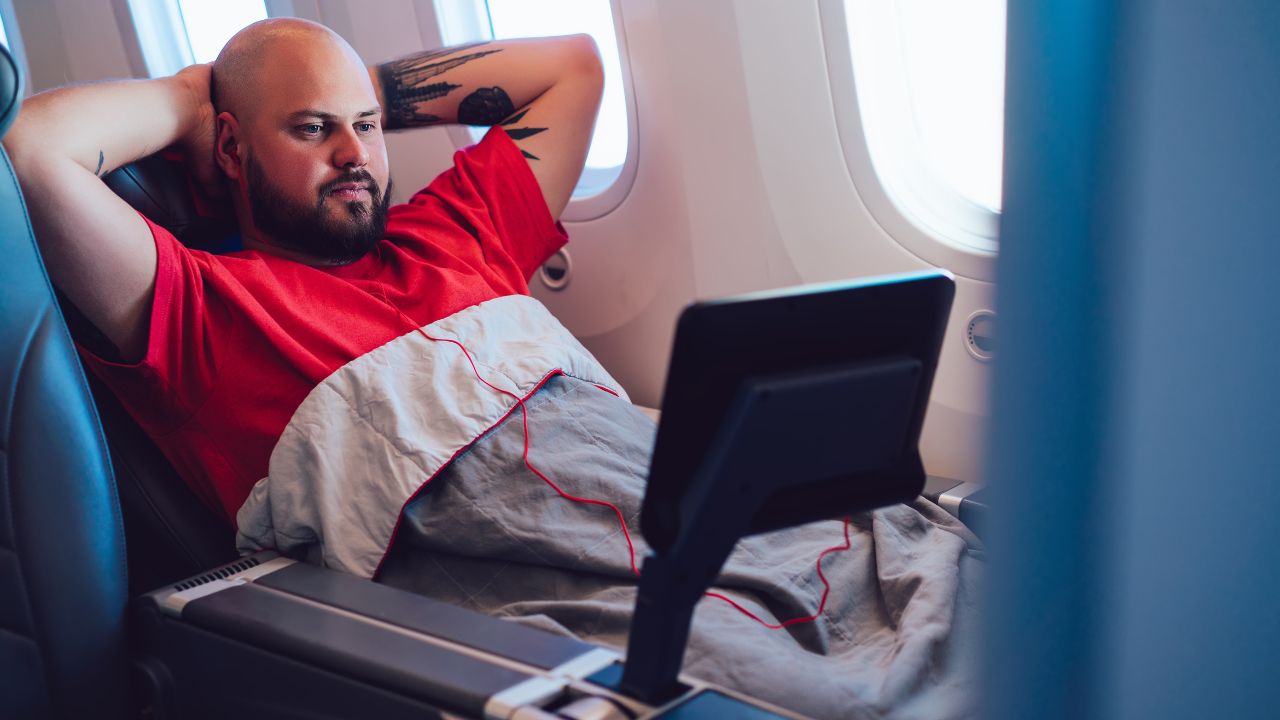 Passenger relaxing with earphones and the entertainment screen on a flight