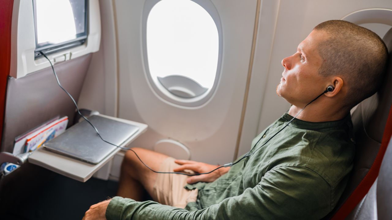 Young man relaxing on a plane with earbuds